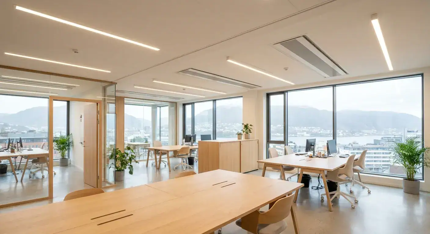 Et moderne kontorlandskap i Bergen med store vinduer og elegant integrert belysning som gir et behagelig lys uten blending